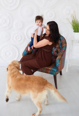 The mother with daughter sitting on the chair near dog