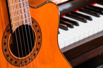 close up of classic guitar over grand piano keys for music background with copy space