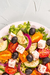 Greek salad with feta cheese, olive, tomatoes, cucumbers, peppers and oil olives in white plate. Restaurant menu. Free space for text. White background.