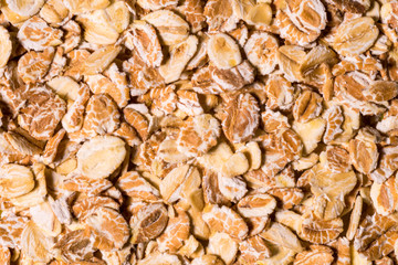 Flakes of porridge oat grits for oatmeal close up pattern background, elevated top view