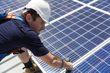Solar panel technician with drill installing solar panels