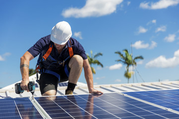 Solar panel technician with drill installing solar panels