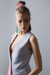 Portrait of beautiful fashion model in sleeveless jacket. Bright makeup and big earrings