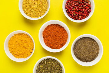 Various spices in bowls on yellow background. Top view. Food background