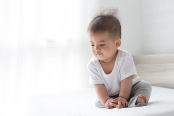 Fototapeta premium Asian baby boy looking something on white bed