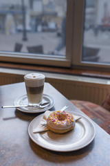 close-up of fresh donut on a plate and a Cup of coffee on the table in the city cafe