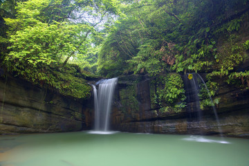 A cool refreshing waterfall tumbling down the cliff into an emerald pond hidden in a mysterious forest of lush greenery ~ Scenic view of a beautiful waterfall and intriguing river potholes in Taiwan