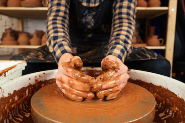 The hands of a man in clay on a potter's wheel mold a vase. The potter works in a pottery workshop with clay. the concept of pottery mastery and creativity