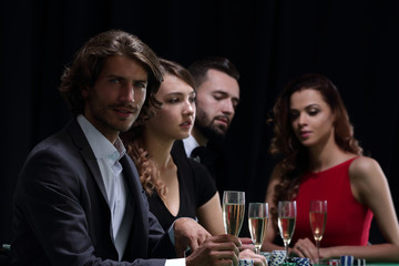 Poker players drink champagne on a black background