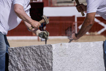 Close-up of the hands of a stonemason, hitting the stone