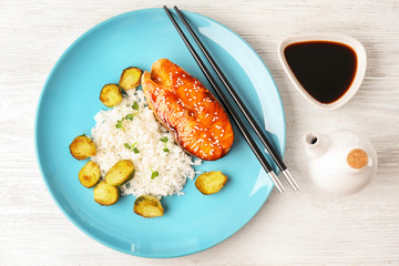 Fish steak served with rice and soy sauce on wooden background
