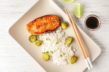 Fish steak served with rice and soy sauce on wooden background