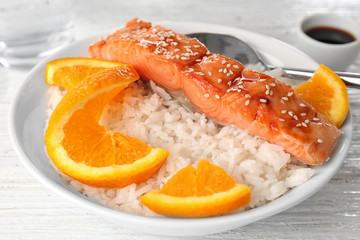 Fish fillet served with rice and orange slices in bowl