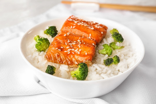 Fish fillet served with rice and broccoli on white fabric