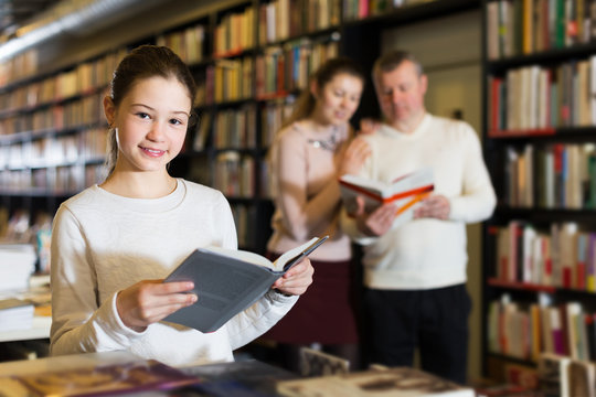 Girl choosing book with parents
