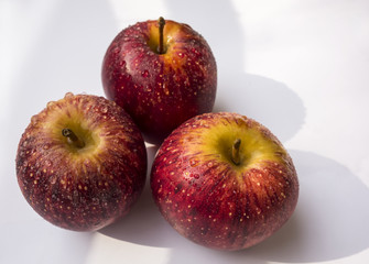 Three bright red apples with water droplets