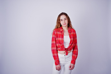 Young girl in red checked shirt and white pants against white background on studio.
