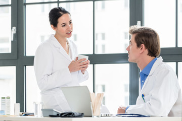 Experienced doctor and pharmacist checking together electronic information on a laptop in the office of a hospital with modern equipment