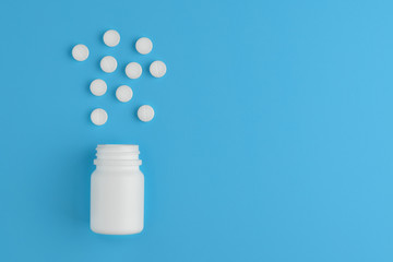 Pharmaceutical medicine pills and bottle on blue background. Copy space for text.