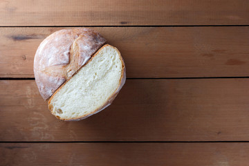 Sliced bread on a wooden background, two halves of wheat bread from a plate on pine boards, French dough for a designer, copy space, rustic style, wooden background, art