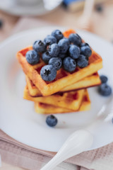 Belgian waffles with blueberries on the light wooden table. Healthy breakfast. 