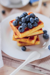 Belgian waffles with blueberries on the light wooden table. Healthy breakfast. 