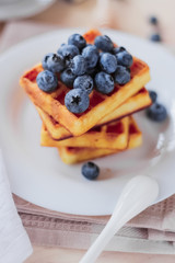 Belgian waffles with blueberries on the light wooden table. Healthy breakfast. 
