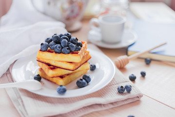 Belgian waffles with blueberries on the light wooden table. Healthy breakfast. 