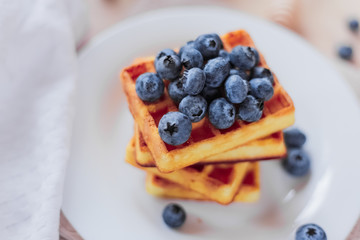 Belgian waffles with blueberries on the light wooden table. Healthy breakfast. 