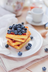 Belgian waffles with blueberries on the light wooden table. Healthy breakfast. 