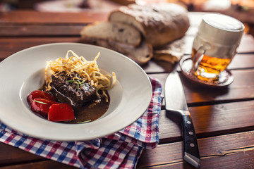 Confit beef steak with sauce fried onion bread draft beer and decoration in pub or restaurant