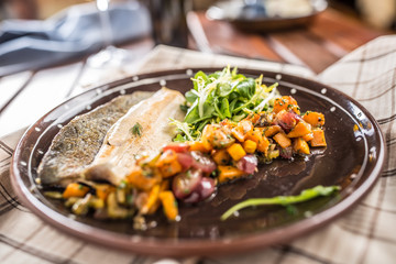Roasted fish fillet with pumpkim pieces and herb decoration in pub or restaurant