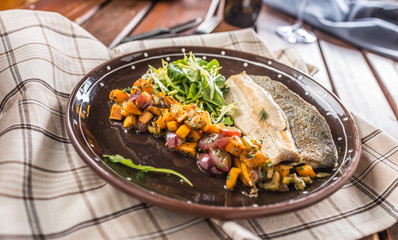Roasted fish fillet with pumpkim pieces and herb decoration in pub or restaurant