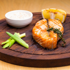 Glazed salmon fillet with sesame close up on a wooden plate