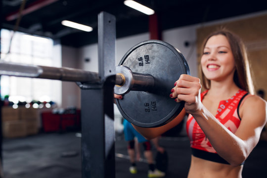 Photo of smiling sportswoman in sports clothes with barbell