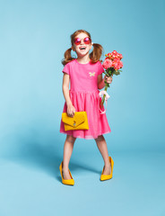 funny child girl fashionista in big mother's   shoes on colored background