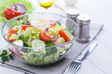 fresh spring salad of vegetables on a white wooden table.