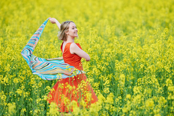 Fototapeta premium Spring and freedom. woman at yellow rape seed meadow