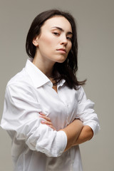 Beautiful girl in a white shirt shows emotions - disorder. On a light background.