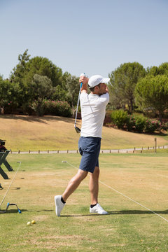 Young golf player practicing on golf driving range