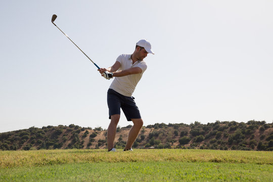 Male golf player swinging before hitting the ball