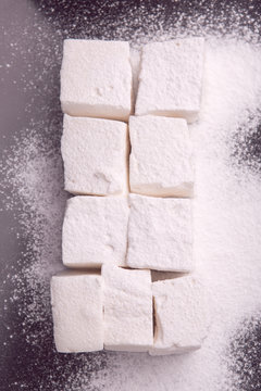 Marshmallow cubes sugar powdered lying on black plate