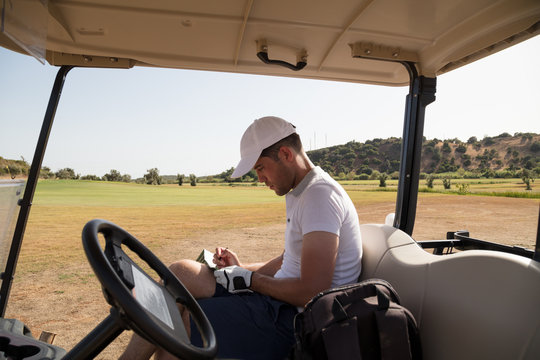 Golfer in golf cart writing down scores on scorecard