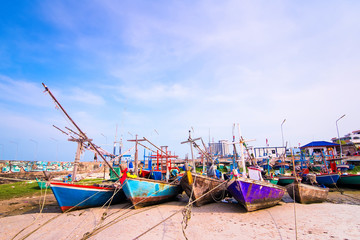 Fototapeta na wymiar Fishing boats aground on the beach over cloudy sky at Prachuap Khiri Khan, Thailand.