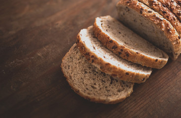 Top view of sliced wholegrain bread on dark ructic wooden  background closeup.