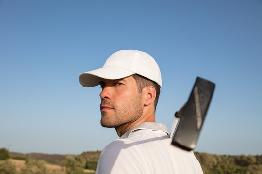 Golf player with club looking into camera