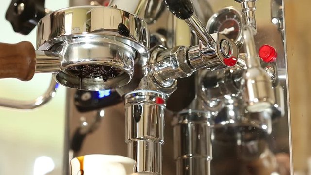 Brewing coffee at home using a nice stainless steeel coffee machine and bottomless portafilter. Barista making coffee at home.