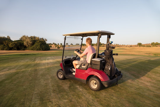Golfer driving a golf cart on the golf course