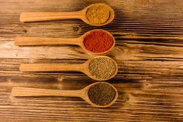 Spoons with the different spices on wooden table. Top view
