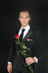 Man in suit with rose on dark background.